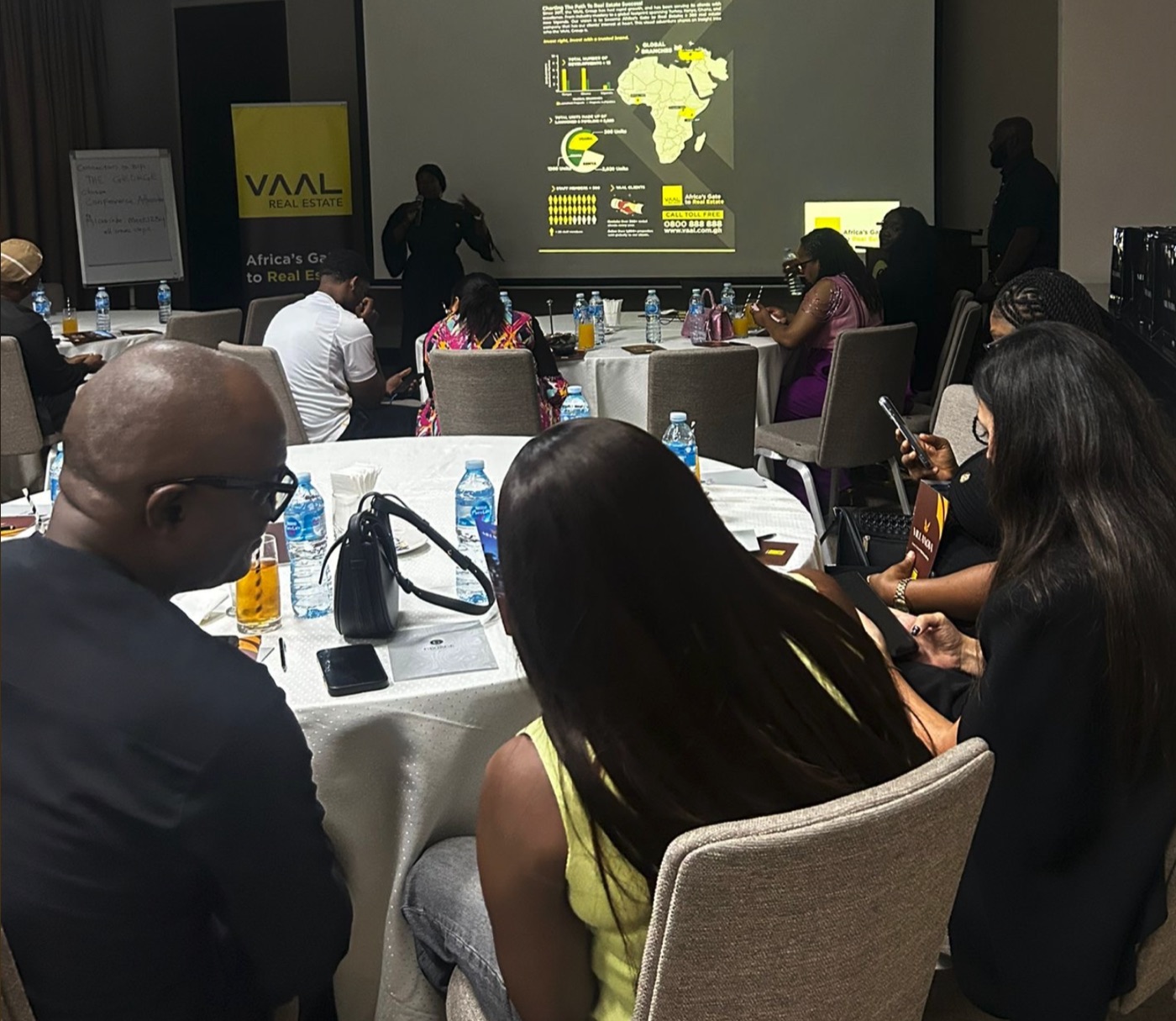 Vaal Real Estate investor presentation in a Lagos meeting room, guests seated at round tables before the brand's Africa expansion slides